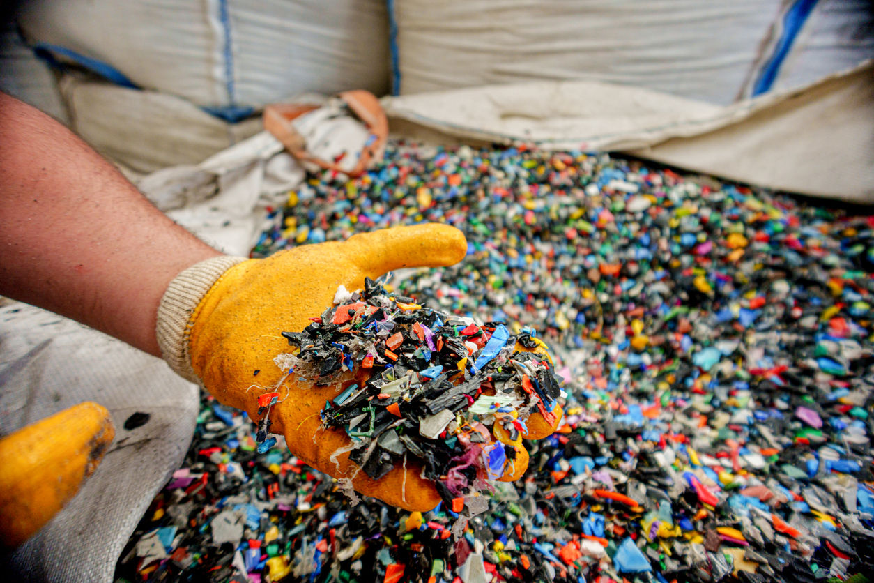 Worker Holding Recycled Plastic Pellets in Hands with Protective Gloves